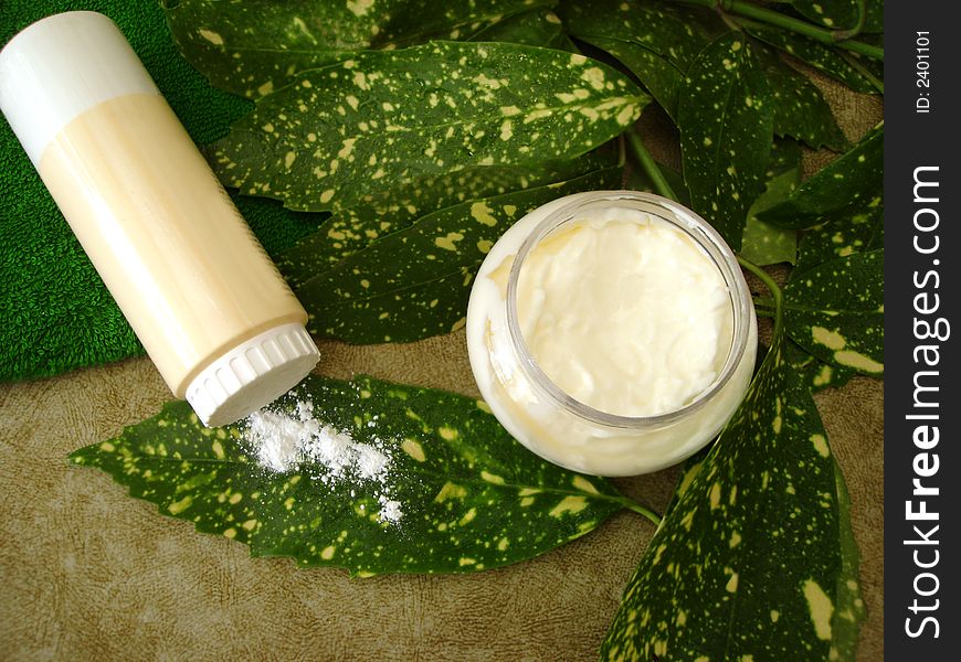 Cream, bottle og powder and towel with green leaves. Cream, bottle og powder and towel with green leaves
