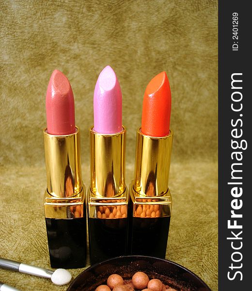 Three lipsticks on brown background