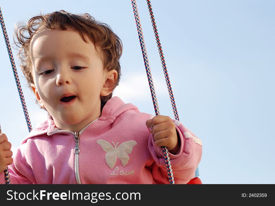 A little child swinging outdoors