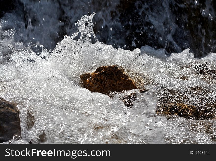 Water flowing beneath rocks at mountain waterfall