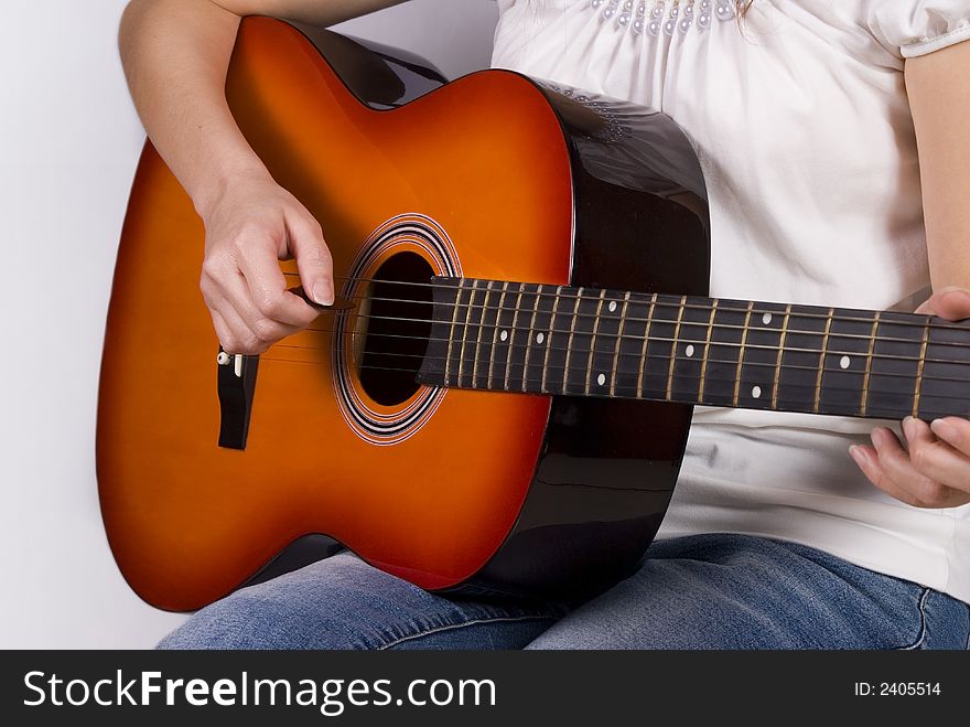 Girl in white and jeans plucking a bridge orange guitar. Girl in white and jeans plucking a bridge orange guitar
