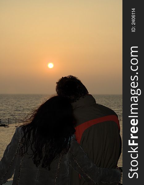 Couple watching sunset arm in arm. Couple watching sunset arm in arm
