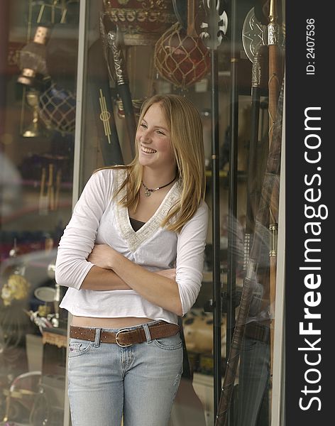 An American teenager enjoys a moment outside a small town store's windows filled with an eclectic assortment of stuff.