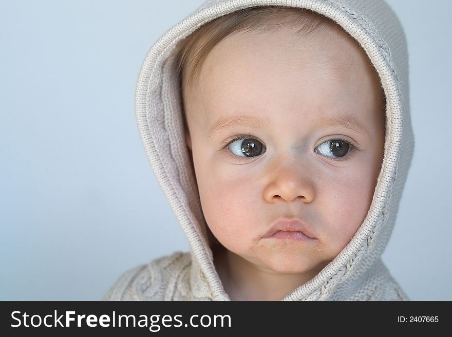 Image of cute baby wearing a hooded sweater, sitting in front of a white background. Image of cute baby wearing a hooded sweater, sitting in front of a white background