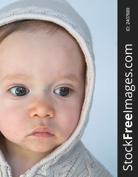 Image of cute baby wearing a hooded sweater, sitting in front of a white background. Image of cute baby wearing a hooded sweater, sitting in front of a white background