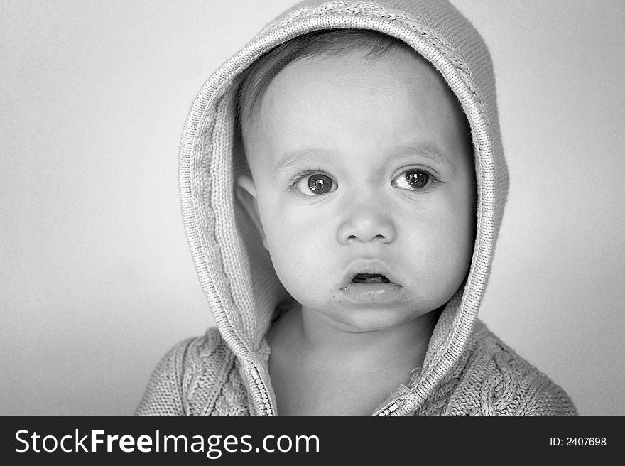 Black and white image of cute baby wearing a hooded sweater. Black and white image of cute baby wearing a hooded sweater