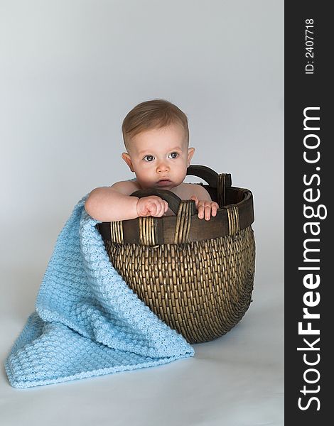 Image of cute baby sitting in a woven basket lined with a blanket. Image of cute baby sitting in a woven basket lined with a blanket