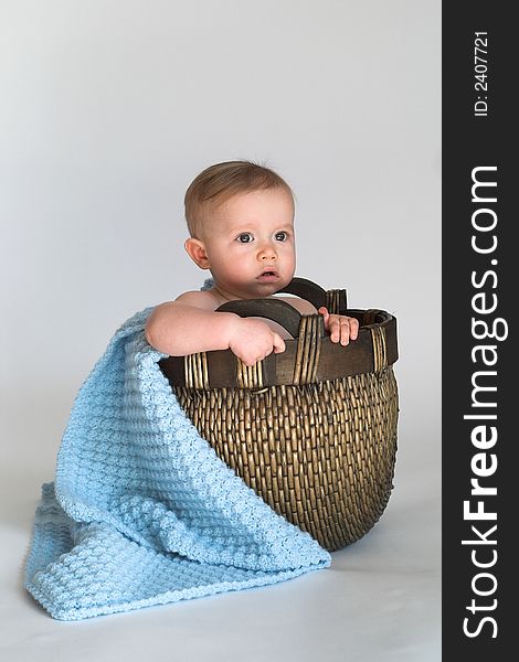 Image of cute baby sitting in a woven basket lined with a blanket. Image of cute baby sitting in a woven basket lined with a blanket
