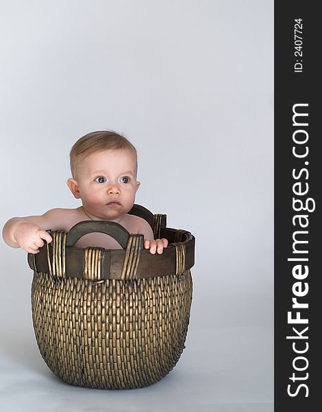 Image of cute baby sitting in a woven basket. Image of cute baby sitting in a woven basket