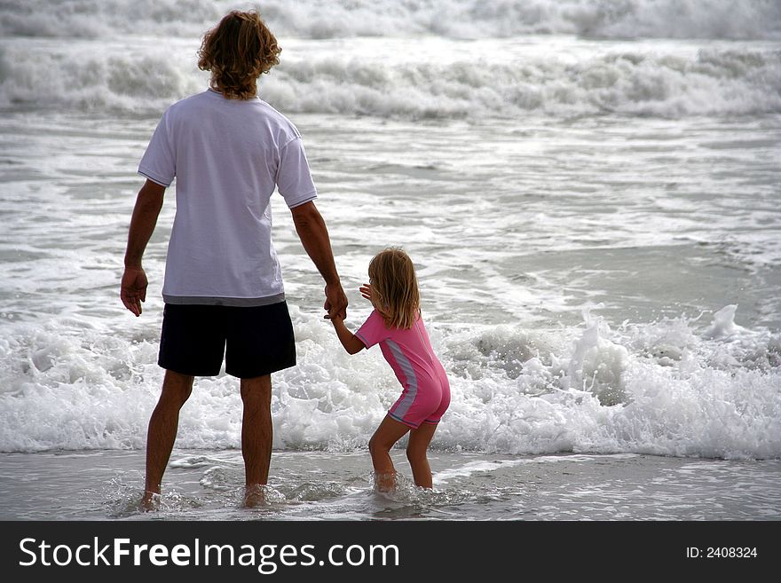 Portrait of a father and daughter playing in the waves on the beach. Portrait of a father and daughter playing in the waves on the beach.