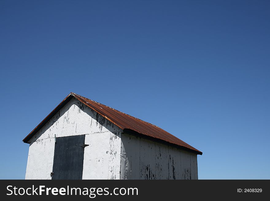 White rural hut and spacious blue sky (barn on the farm). White rural hut and spacious blue sky (barn on the farm).