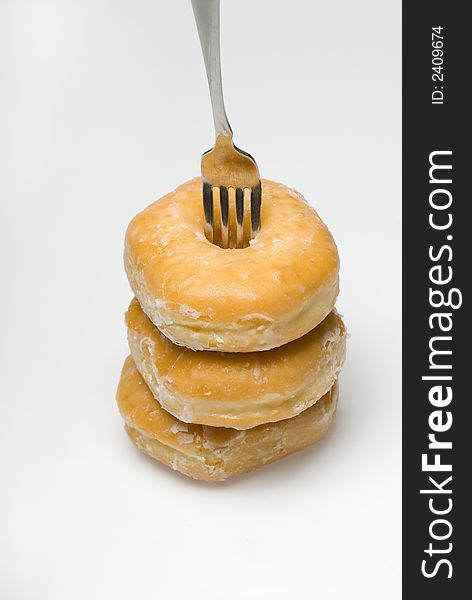 Three glazed donuts stacked isolated on white with fork. Three glazed donuts stacked isolated on white with fork