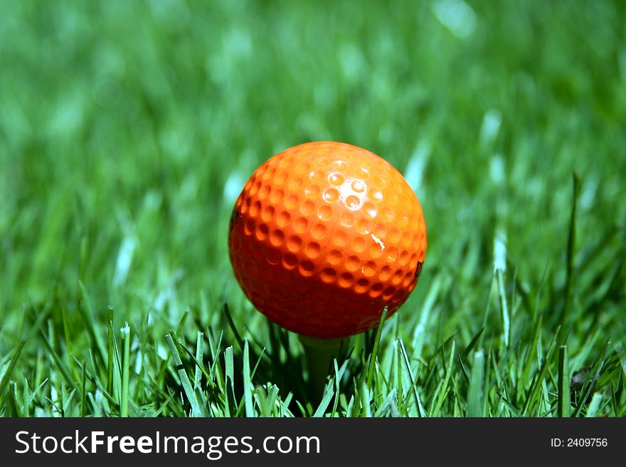 An orange golf ball on a tee