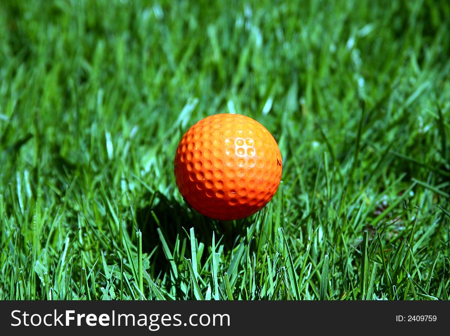 An orange golf ball on a tee