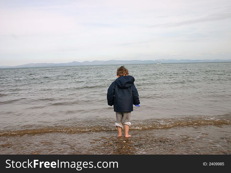 Little boy on beach looking toward the sea, Llanbedrog Beach, North Wales. Little boy on beach looking toward the sea, Llanbedrog Beach, North Wales
