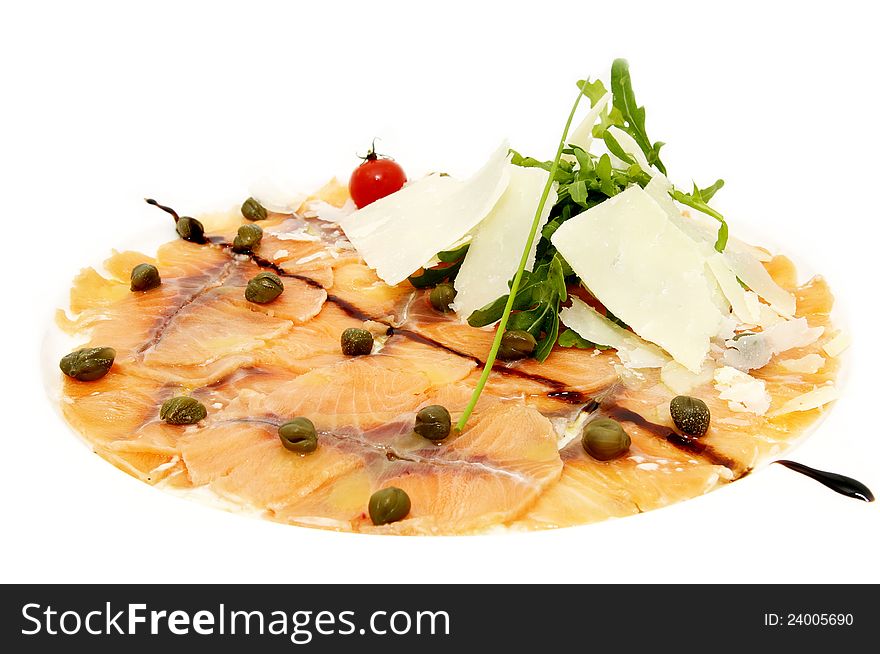 Fish carpaccio with green on a white plate