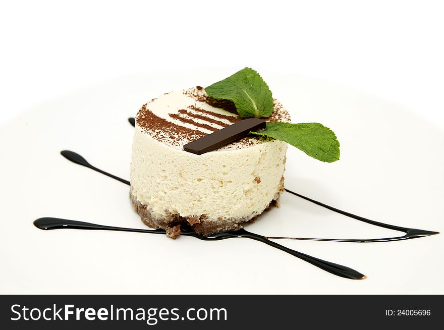 Creamy dessert is decorated with mint on a white plate. Creamy dessert is decorated with mint on a white plate