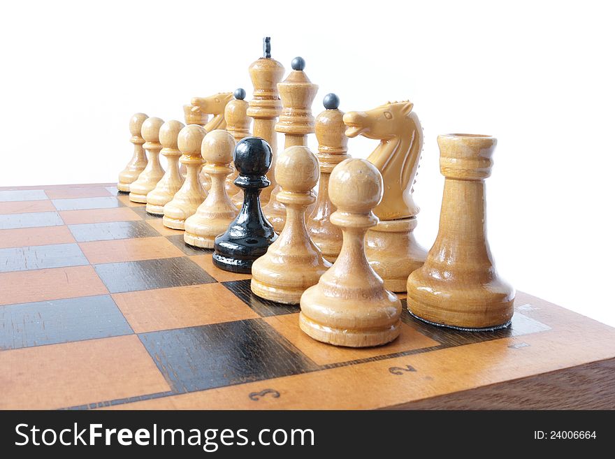 A black pawn amongst white chess pieces.