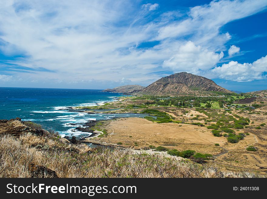 Aerial of Pacific ocean and Hawaii coast with waves hitting rocks. Diamond's Head on the background and blu sky with cloud strips. Aerial of Pacific ocean and Hawaii coast with waves hitting rocks. Diamond's Head on the background and blu sky with cloud strips.