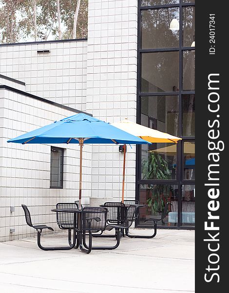 Patio furniture at outdoor cafe with blue and yellow umbrella