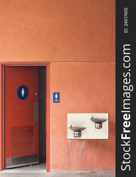 Orange wall women toilet with front sink