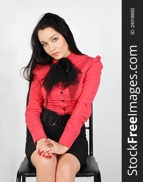 Young girl wearing skirt and red shirt sits on chair in studio. Young girl wearing skirt and red shirt sits on chair in studio