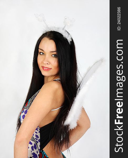 Happy beautiful girl with white wings wearing dress smiles in studio