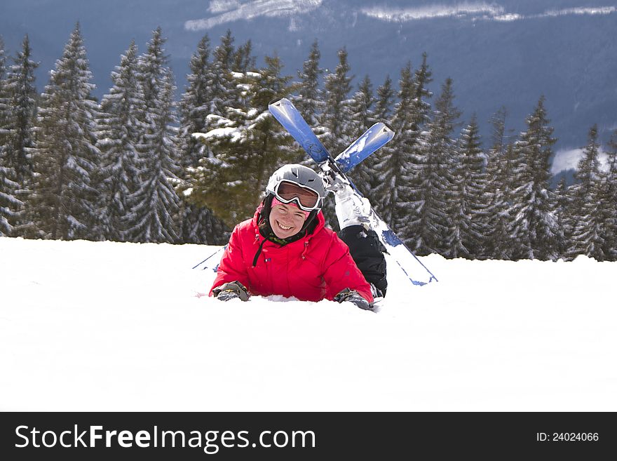 Woman with skis lies on the snow in a forest background. Woman with skis lies on the snow in a forest background