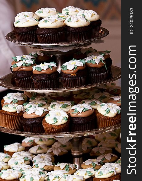 Miniature chocolate cupcakes with a flower shaped frosting design on display. Miniature chocolate cupcakes with a flower shaped frosting design on display