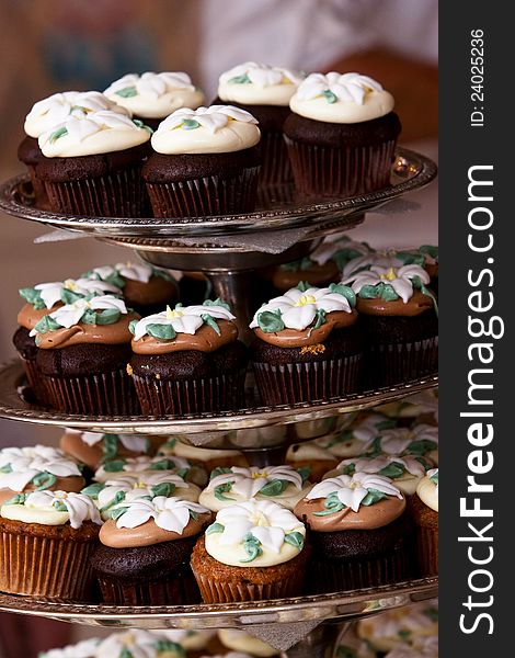 Miniature chocolate cupcakes with a flower shaped frosting design on display. Miniature chocolate cupcakes with a flower shaped frosting design on display