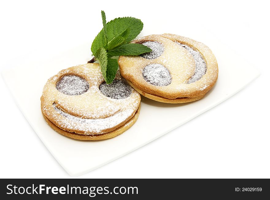 Smiley cookies decorated with mint on a white plate
