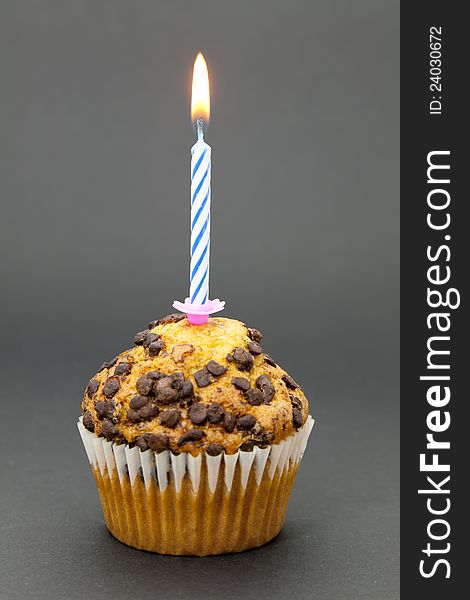 Delicious chocolate cupcake with a lit candle and the black background