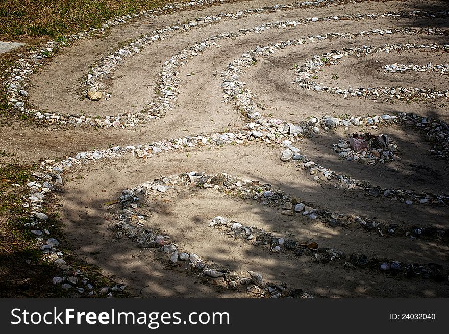 Looking down on a stone and sea shell maze or labyrinth with dirt paths. Looking down on a stone and sea shell maze or labyrinth with dirt paths