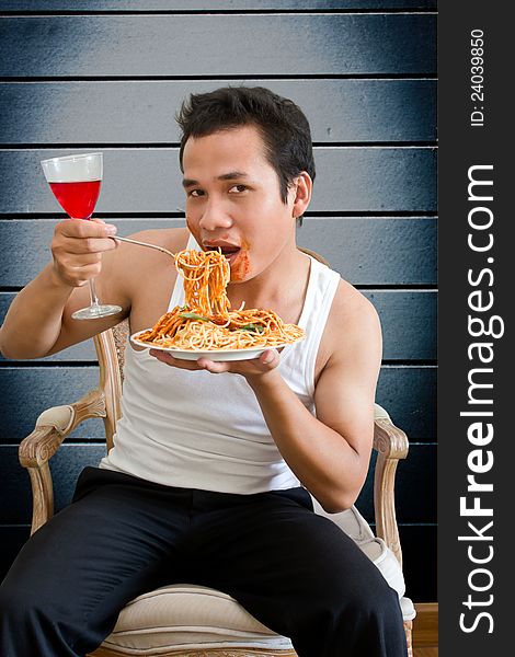 Man eating spaghetti with behind old wall