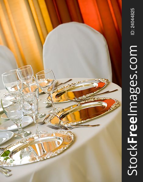 Wedding table with white tableclothes and silver platters set for fine dining. Wedding table with white tableclothes and silver platters set for fine dining