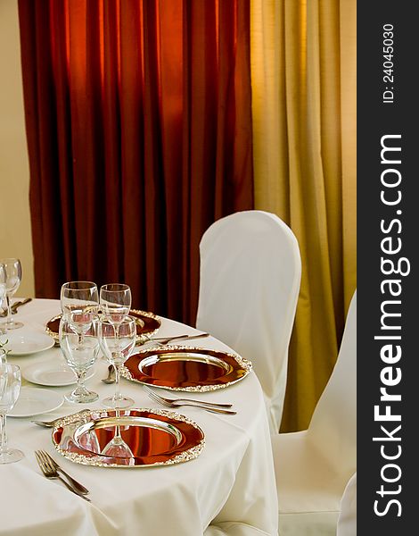 Wedding table and chairs with white tableclothes and silver platters set for fine dining. Wedding table and chairs with white tableclothes and silver platters set for fine dining