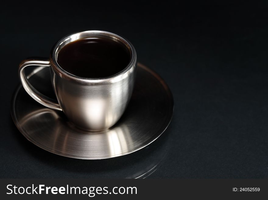 Stylish modern steel coffee cup and saucer on dark background. Stylish modern steel coffee cup and saucer on dark background