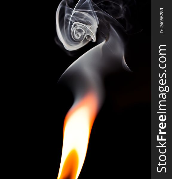 Flame isolated against a black background with smoke swirling above. Flame isolated against a black background with smoke swirling above