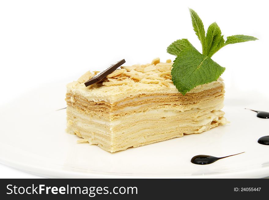 Piece of layer cake decorated with a mint on a white plate. Piece of layer cake decorated with a mint on a white plate