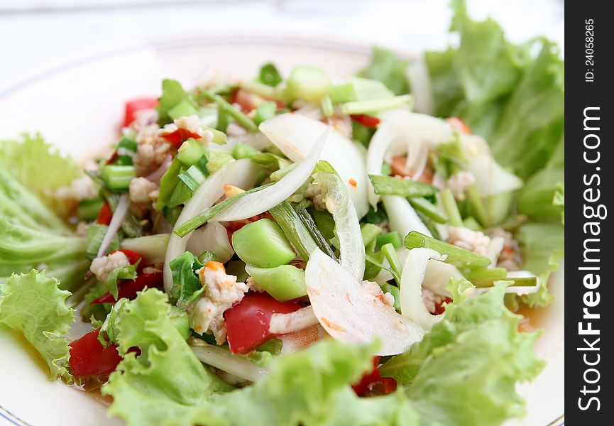 Thai food, spicy salad with pork and green vegetables