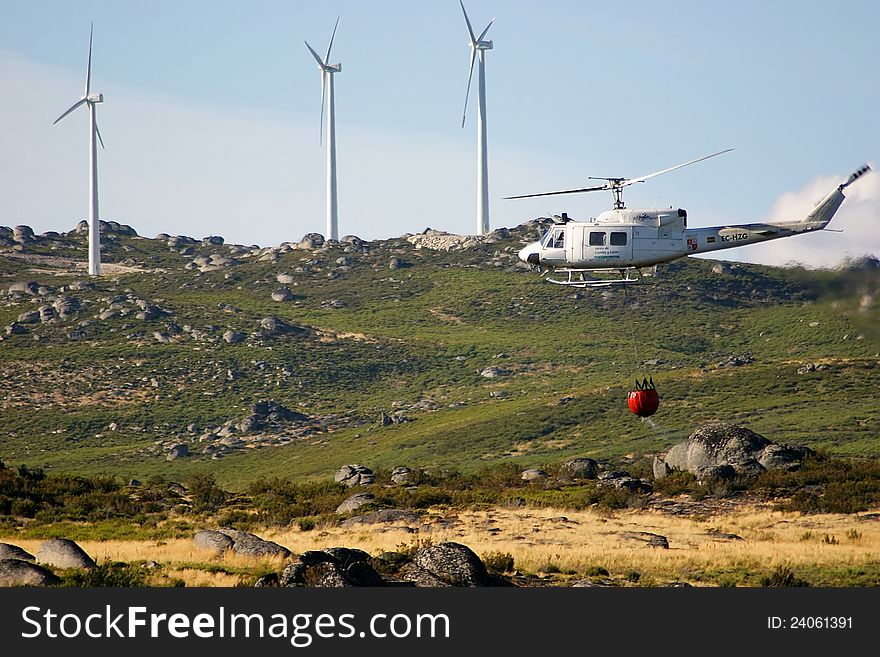 Firefighter helicopter in mission. Background of mountain an cloudy sky