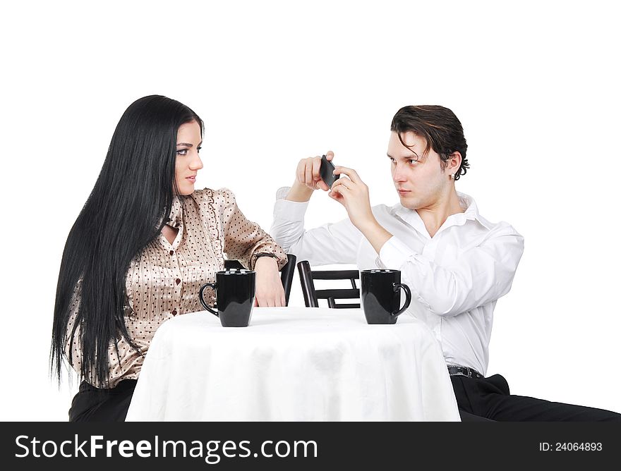 Young men taking picture of girlfriend on smart phone in cafe, isolated