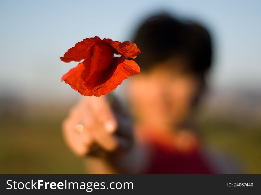 Portrait of a defocused woman with a poppy in her hand
