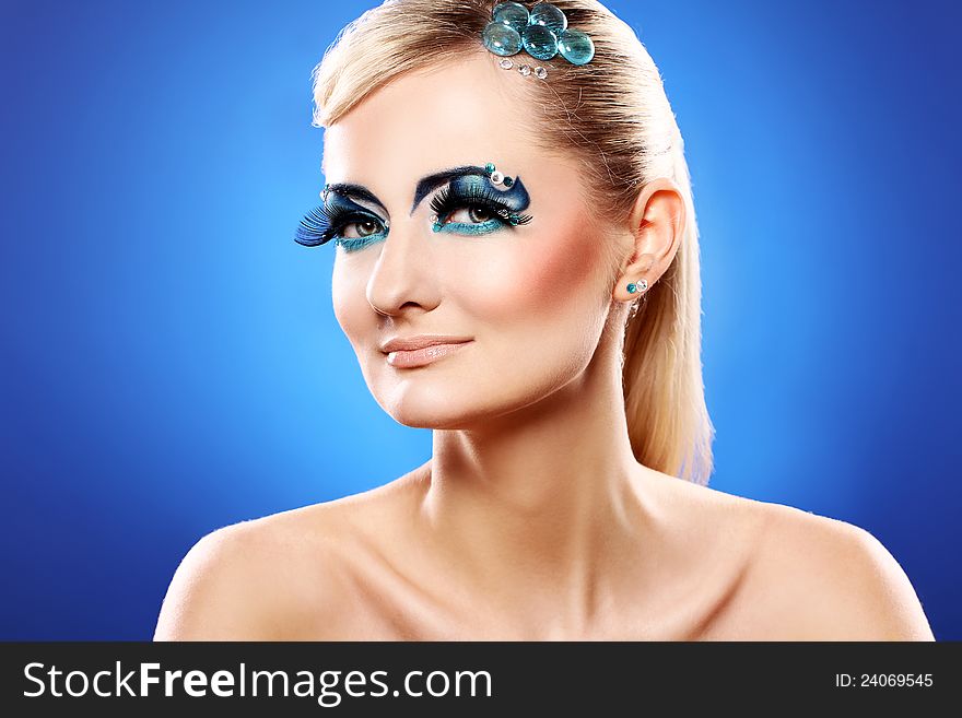 Beautiful blonde with artistic makeup over blue background