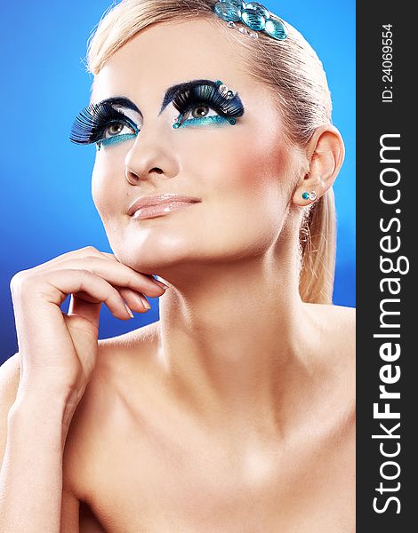 Beautiful blonde with artistic makeup over blue background