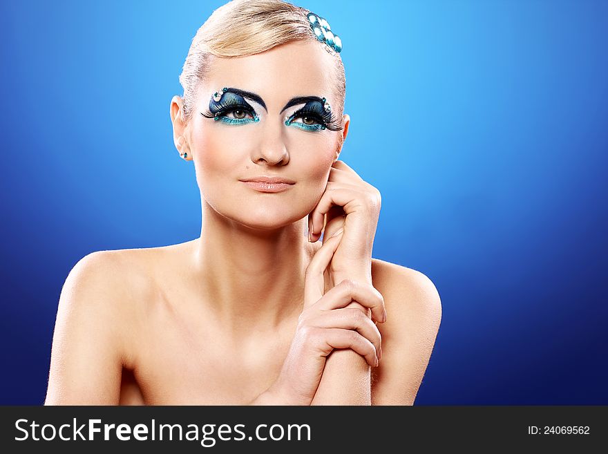 Beautiful blonde with artistic makeup over blue background