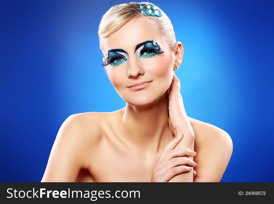 Beautiful blonde with artistic makeup over blue background