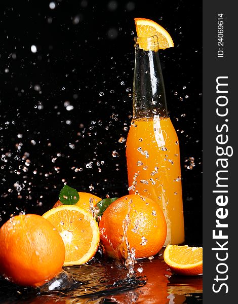 Fresh orange drink with splashes of water over black background