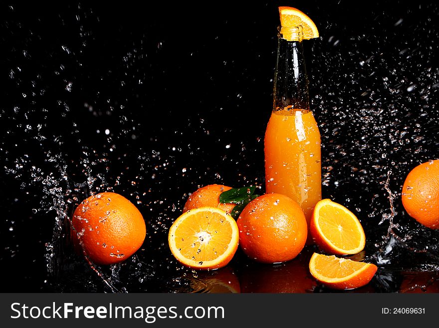 Fresh orange drink with splashes of water over black background