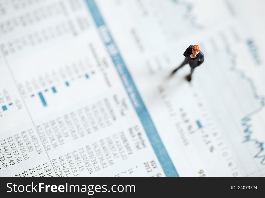 Conceptual picture of abusinessman figure standing on a stock chart on financial pages from a newspaper. Conceptual picture of abusinessman figure standing on a stock chart on financial pages from a newspaper